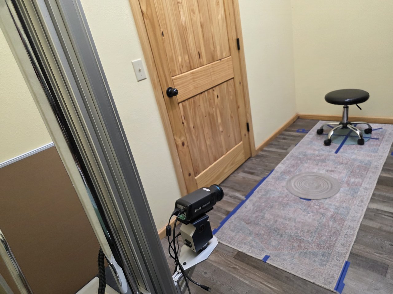 Thermal camera facing a marked floor area and stool in the imaging room.