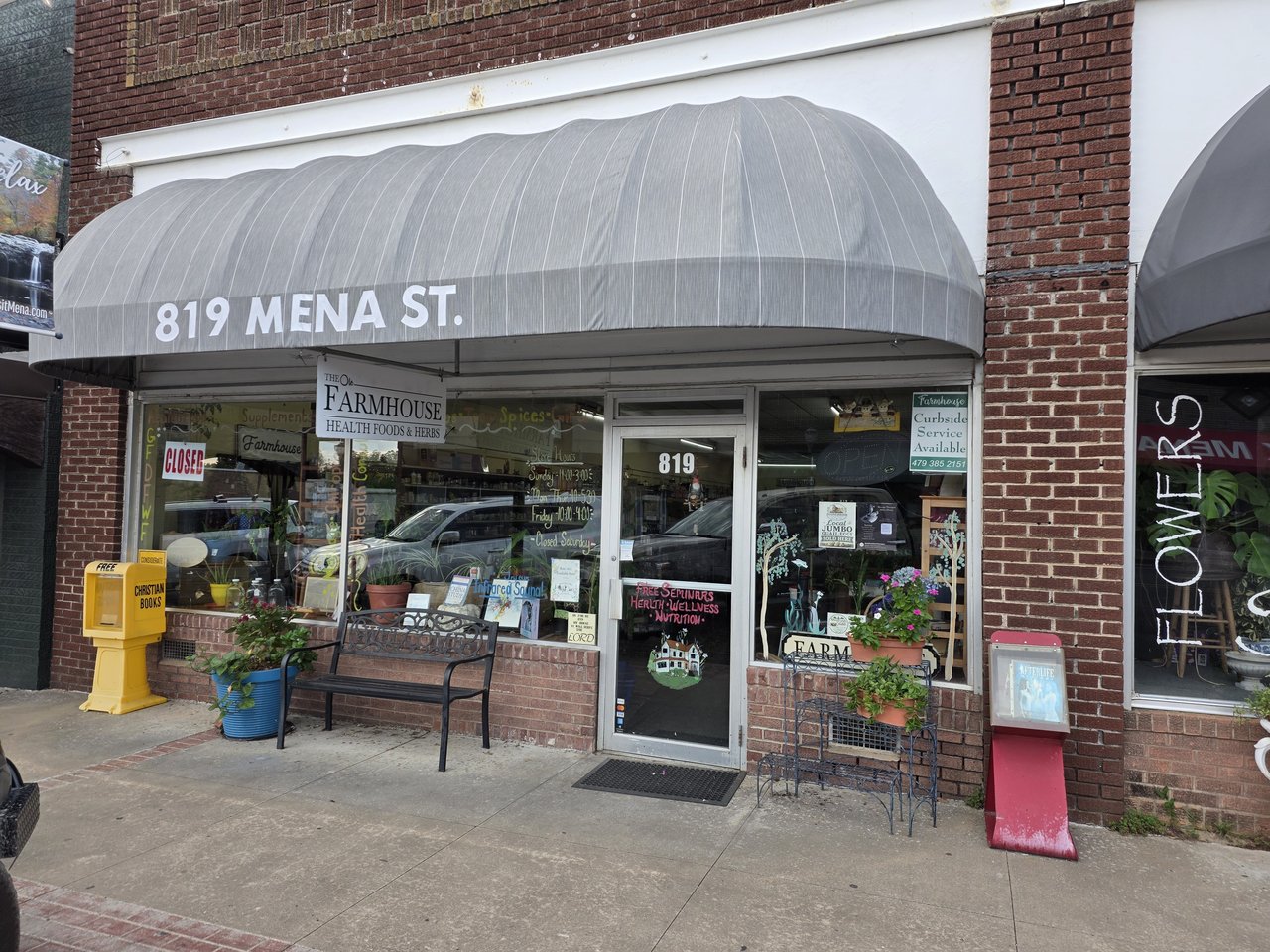 The glass entrance beneath the 819 Mena St. awning, with plants and storefront displays.